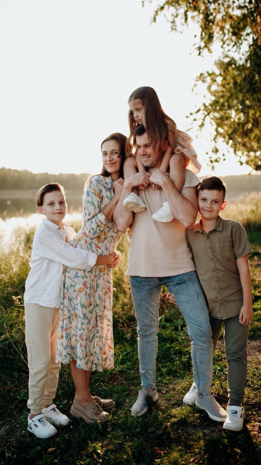 Une famille de cinq personnes debout au bord d'un lac au coucher du soleil