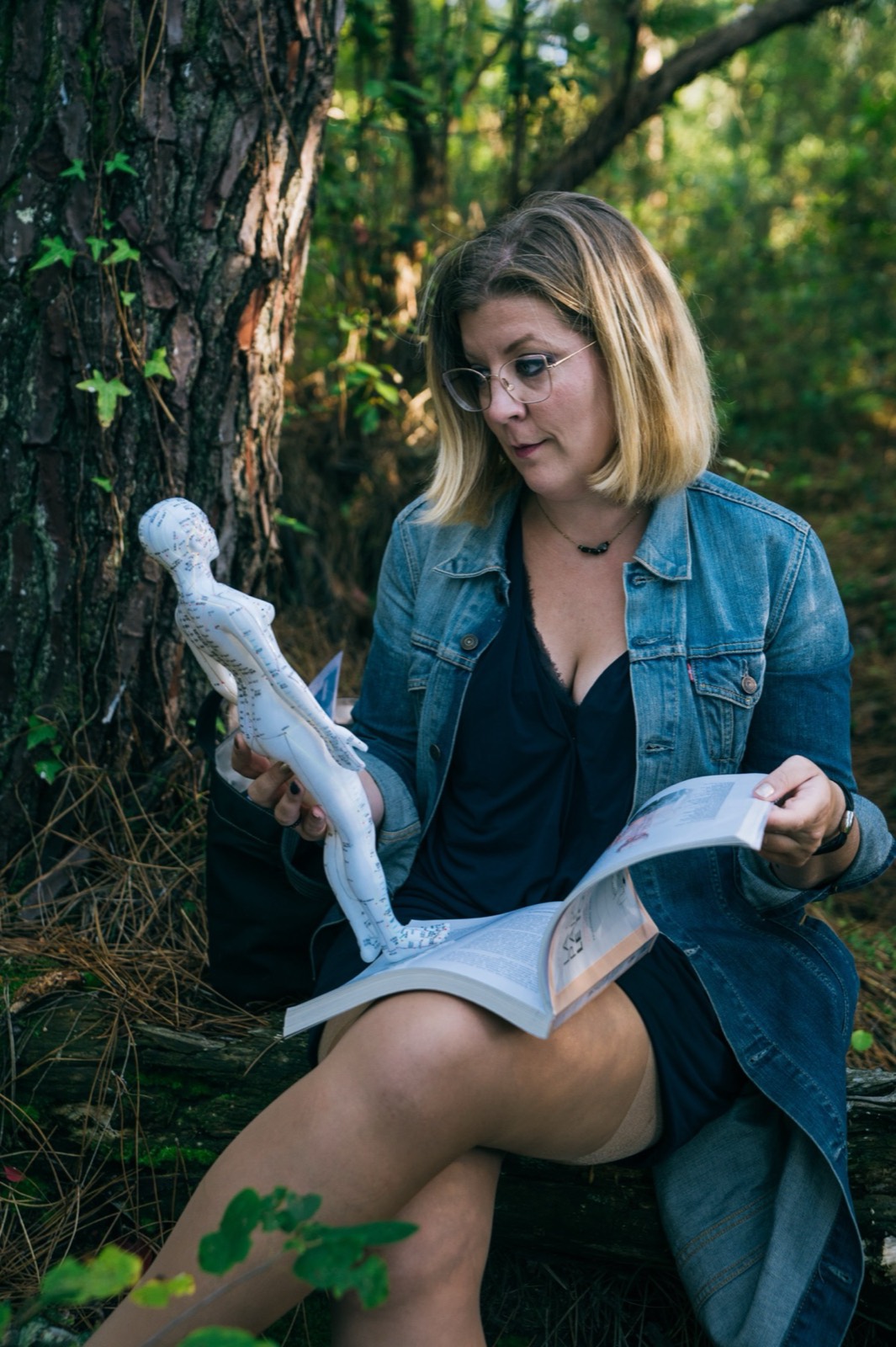 Mary Picart assise en forêt, un livre ouvert sur les genoux